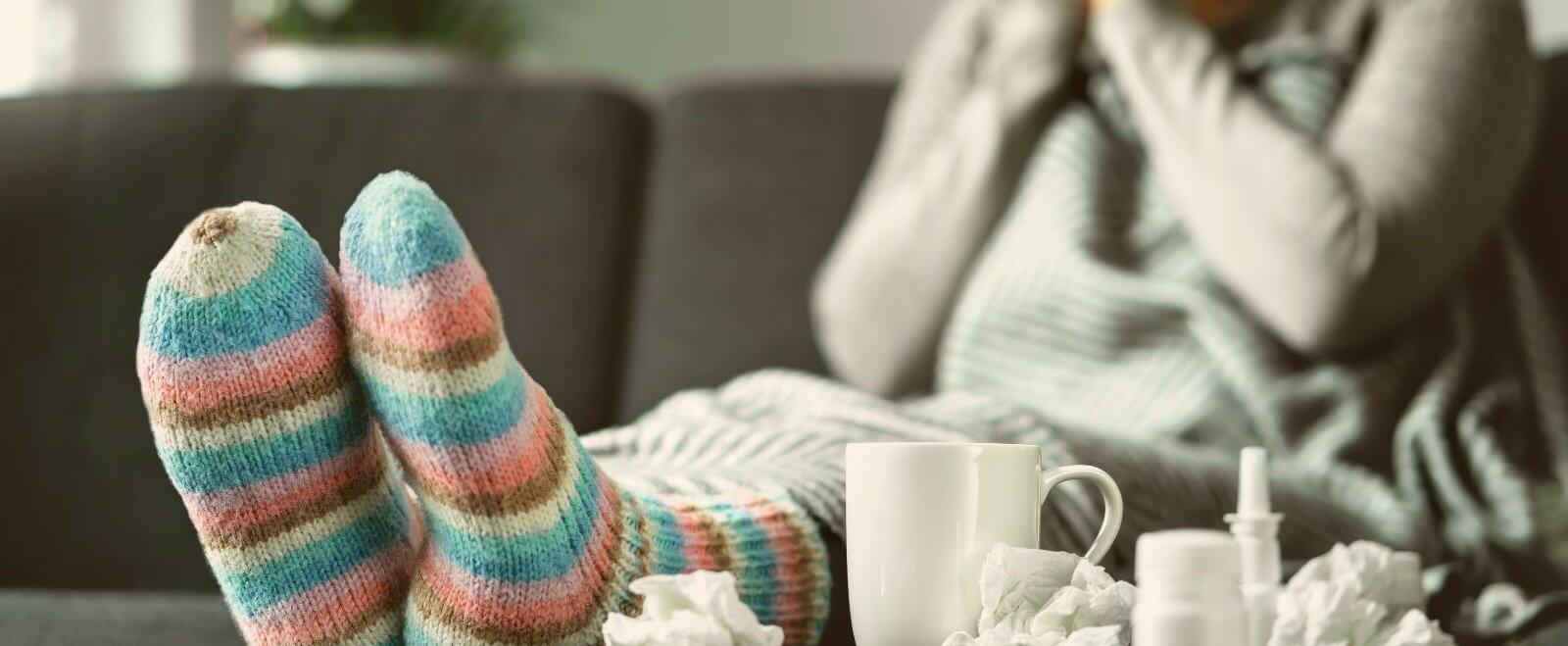 Erkältete Person mit dicken Socken: Krank arbeiten: Was macht die Selbständigkeit mit mir?