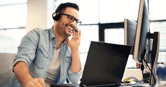 Lächelnder lexoffice Kundenservice arbeitet mit einem Headset vor seinem Computer
